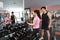 Muscular woman working out in gym doing exercises with dumbbells at biceps, strong male naked torso abs