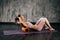 Muscular young athletic woman with perfect beautiful body in activewear using foam roller massager on upper back lying