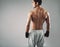 Muscular young male boxer standing on grey background