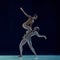 Muscular young man and beautiful woman, ballet dancers making artistic performance, dancing against blue studio