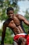 Muscular young man exercising at the sports field. African man looking to the side while doing horizontal bar exercises