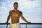 Muscular young man leaning on hand-railing on cruise ship