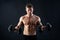 Muscular young man lifting weights on black background