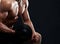 Muscular young man lifting weights on black background