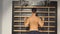 Muscular young man, training back on wall bars