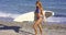 muscular young woman surfer with her board