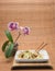 Mushroom dish with vegetables on a table with bamboo tablecloth and orchid