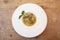 Mushroom garlic chive broth in white bowl garnished with basil, old wood background
