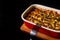 Mushroom julienne or mushroom casserole in a baking dish stands on a Board on a black background