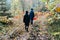 Mushroom pickers go to the forest for mushrooms along the path in autumn, teenage children in raincoats in autumn