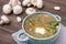 Mushroom soup with greens and sour cream in a green plate, napkin, mushrooms, wooden background