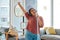 Music, headphones and woman singing while cleaning home, dancing and having fun. Singer, dance and female spring