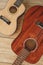 Music from heart. Vertical top view of the acoustic and ukulele guitars lying close to each other on the wooden floor