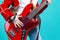 Music Ideas and Concepts. Closeup of Hands of Caucasian Guitar Player Posing With Bass Guitar In Fashionable Red Jacket Over