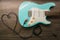 Music love concept. Wire jack heart guitar. Light blue electric guitar in a wood texture