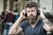 Music lover concept. Man with long beard and mustache with wireless headphones on head, defocused urban background