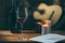 Music notes, wine and candle on table, with a guitar in the background