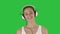 Music, people and technology concept - happy smiling woman with headphones walking on a green screen, chroma key.