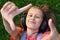 Musical cheerful mood. A young girl lies on the grass and listens to music on headphones