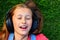 Musical cheerful mood. A young girl lies on the grass and listens to music on headphones