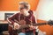 A musician man in glasses playing guitar and recording the sound in the studio