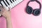 Musician is playing on keyboard with studio headphone on pink