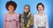 Muslim, African and European girls isolated look at the camera, internationality, blue background, friendship of nations