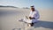 Muslim Arabian UAE Sheikh architect sitting with laptop on sand