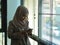 Muslim businesswoman using smartphone while relaxed standing in office