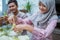 muslim couple asian making ketupat rice cake at home using palm leaf
