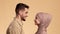 Muslim Couple In Love Smiling One Another Over Beige Background