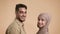 Muslim Couple Turning Heads And Smiling Standing Over Beige Background