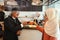 Muslim customer businessman wearing black suit drinking coffee at counter with young muslim barista businesswoman background