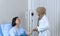 Muslim female doctor holding hand of the elderly patient sitting on the bed at hospital, takes care and cheerful concept