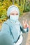 Muslim girl in a medical mask makes a selfie. Portrait of islamic arabian woman in park during a pandemic.