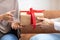 Muslim Husband Giving Gift Box To Wife Indoors, Closeup, Cropped