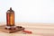 Muslim lantern Fanous, dried dates and prayer beads on table against light background