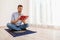 Muslim man reading Koran on prayer rug indoors