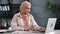 Muslim positive businesswoman in hijab working with laptop in modern loft office at daytime.