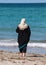 Muslim woman in black robe and white head scarf looking out at b