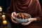 A Muslim woman gracefully holds a bowl of dates, breaking her fast traditionally