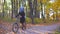 Muslim woman in a hijab and with a backpack with a bicycle goes through a sunny autumn park, sun glare,slow mo