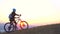 Muslim woman in a hijab with a backpack with a bicycle goes uphill and looks at sunset,slow mo