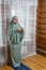 A Muslim woman in a light dress for prayer prays while standing on a mat with a rosary in her hands