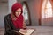 Muslim Woman Reading Koran Or Quran Wearing Traditional Dress At The Mosque