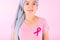 Muslim woman wearing a hijab with a ribbon on her chest shows prevention of breast cancer. On a pink backdrop, breast cancer