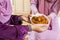 Muslim women holding a bowl of chicken rendang