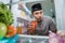 muslim young man cheating and drinking a a glass of water or juice in the fridge while fasting