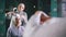 Muslim young woman preparing islamic wedding headdress for young bride in front of mirror