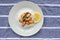 Mussel risotto on white plate on table. Top view of white rice with seafood and lemon slice on striped cloth napkin background.